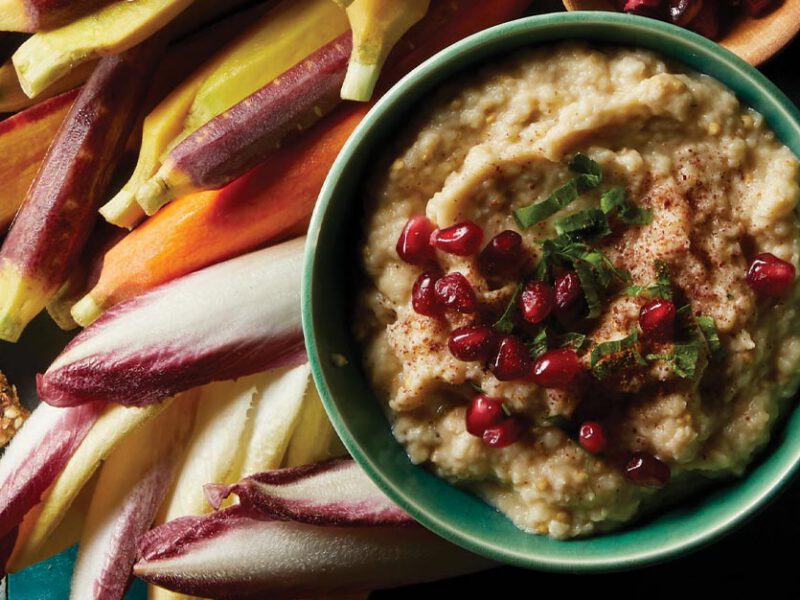 Moutabal (Eggplant Dip) in a turquoise bowl surrounded by carrots and endive