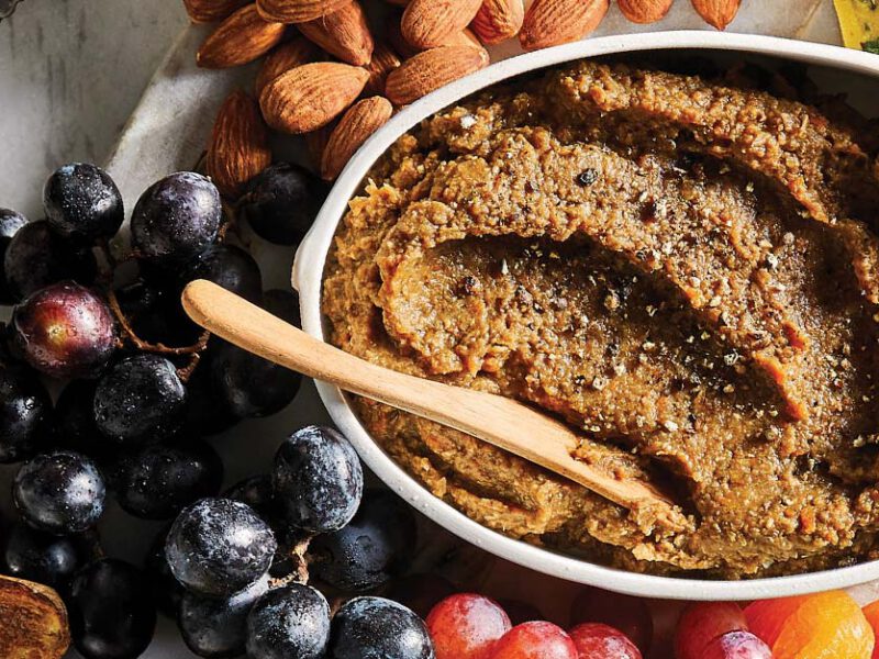 Porcini-Lentil Vegan Pâté in a white oval dish surrounded by fresh fruit and nuts