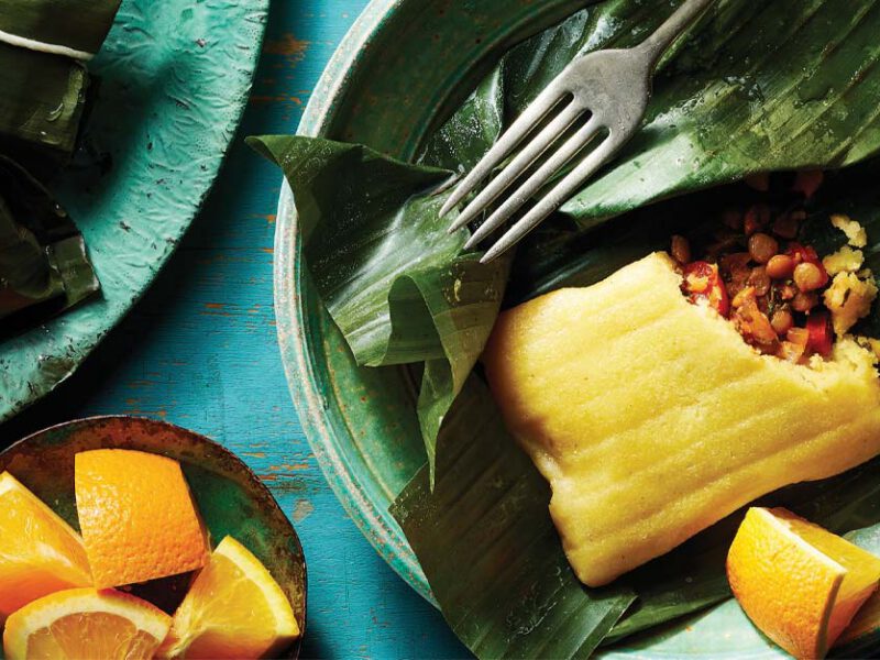 Vegan Pasteles with Lentils in banana leaves on a green wooden plate