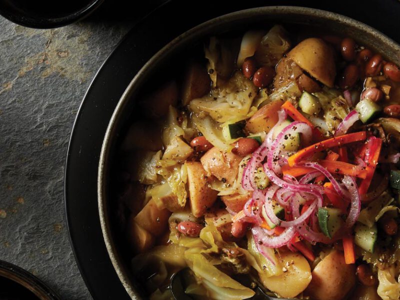 Instant Pot Cabbage and Potato Soup with Pickled Veggies in a gray ceramic bowl against a stone background