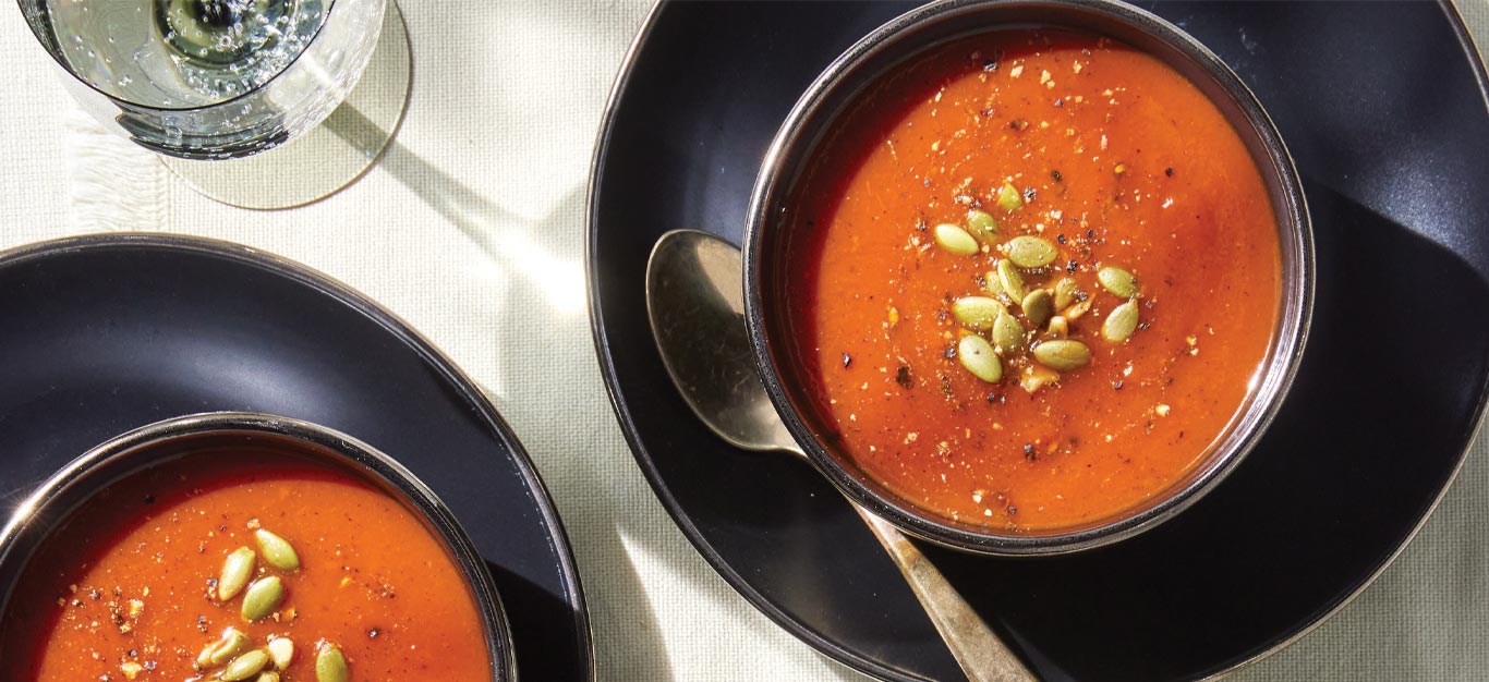 Roasted Red Pepper and Tomato Bisque for Two in black ceramic bowls on black ceramic plates