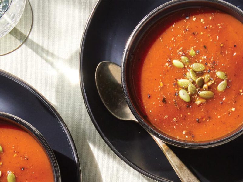Roasted Red Pepper and Tomato Bisque for Two in black ceramic bowls on black ceramic plates