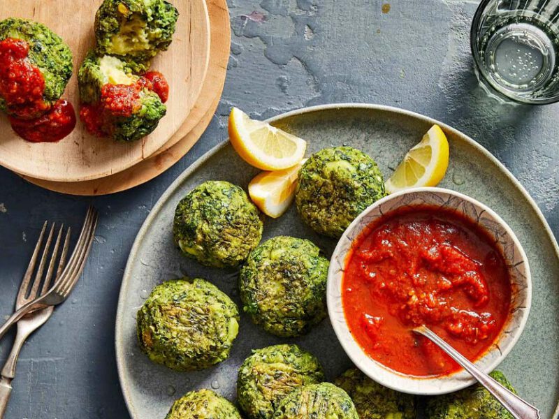 Cheesy Vegan Stuffed Spinach Bites on a gray plate with a small bowl of marinara sauce for dipping