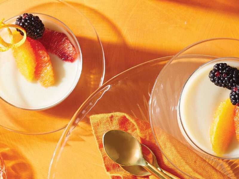 Orange Vegan Panna Cotta with Blackberries in glass dishes against an orange background