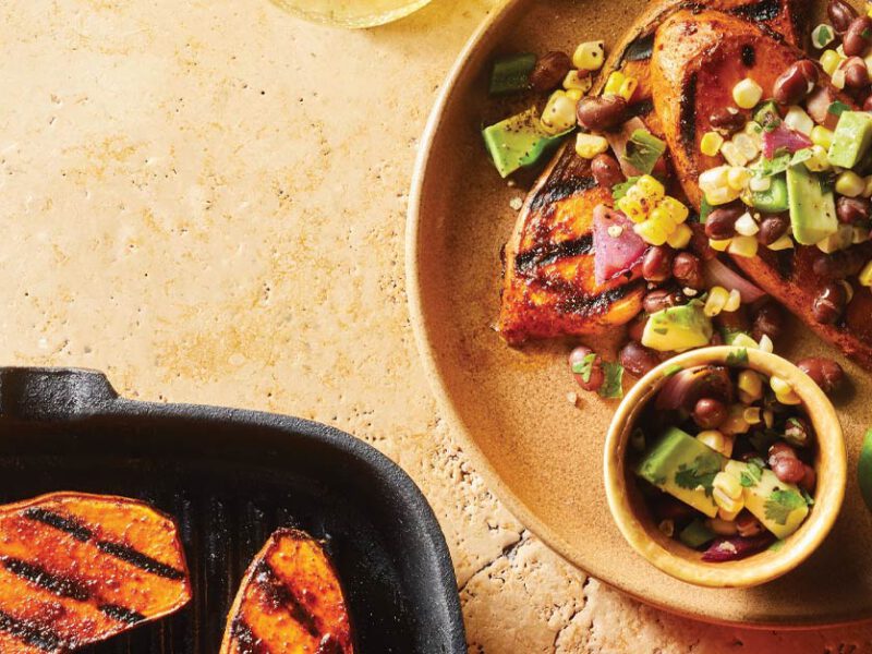 Sweet Potato Steaks with Grilled Salsa on a beige plate with a metal fork and lime wedges