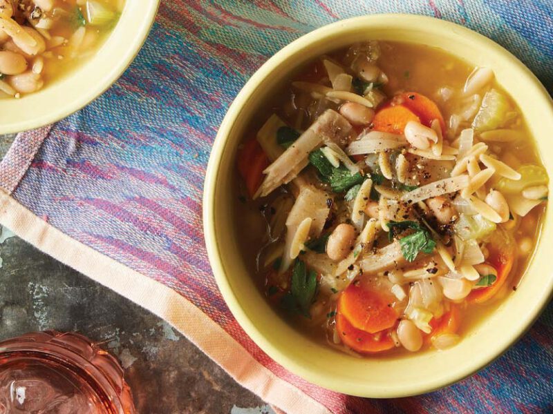 Lemon Orzo Soup with Jackfruit in yellow bowls against a colorful cloth napkin