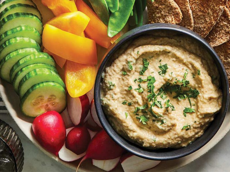 Oil-Free Baba Ghanoush in a small gray bowl surrounded by fresh veggies and crackers