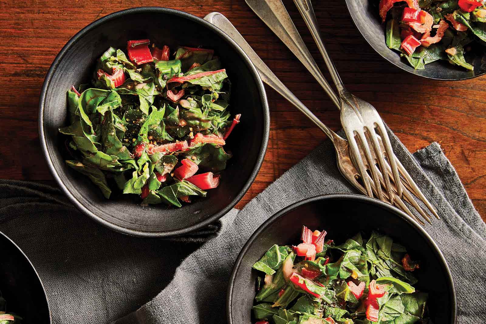Ethiopian Collard Greens and Chard in gray bowls against a dark wood tabletop