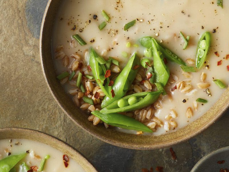 Caramelized Garlic and Potato Soup topped with snap peas in beige bowls