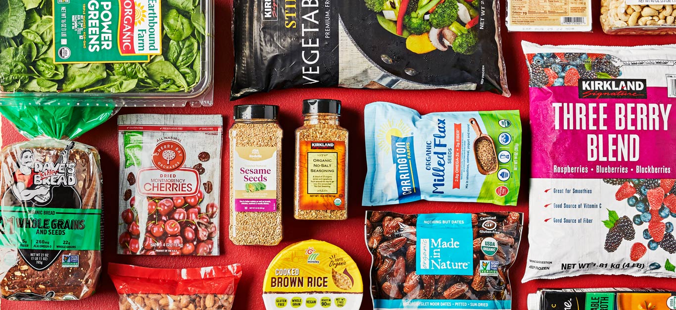 An array of healthy vegan Costco products, including whole grain bread, almonds, salt-free seasoning blends, brown rice, and frozen berries