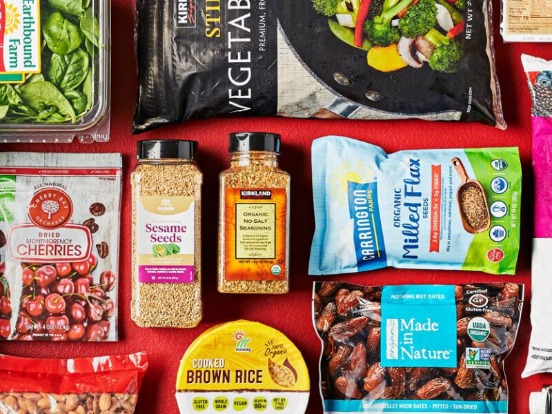 An array of healthy vegan Costco products, including whole grain bread, almonds, salt-free seasoning blends, brown rice, and frozen berries