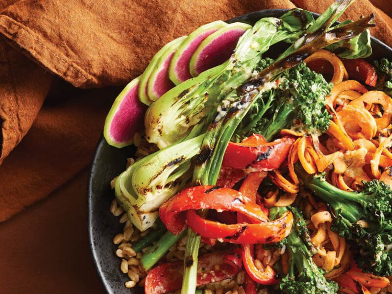 Miso-Ginger Grilled Vegetable Farro Bowls against an orange backdrop with orange cloth napkins