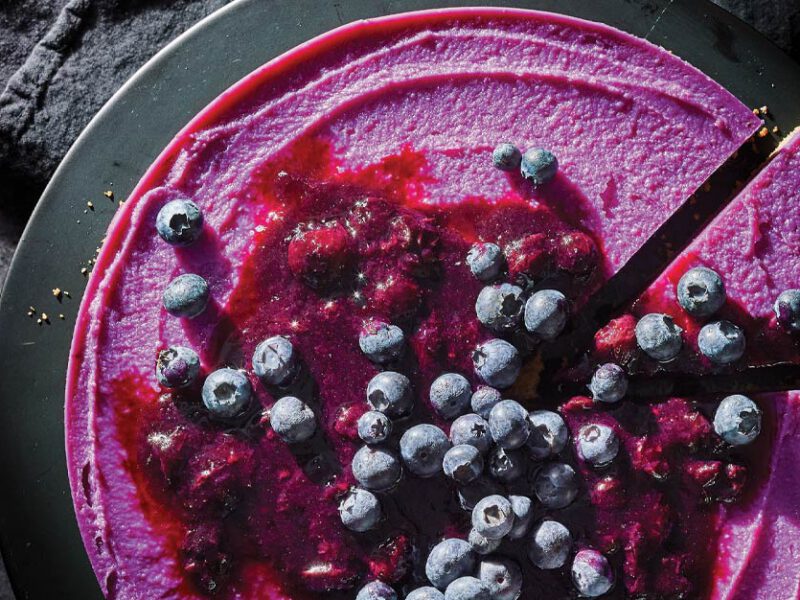 The Great Purple Sweet Potato Pie topped with fresh blueberries on a gray cake platter