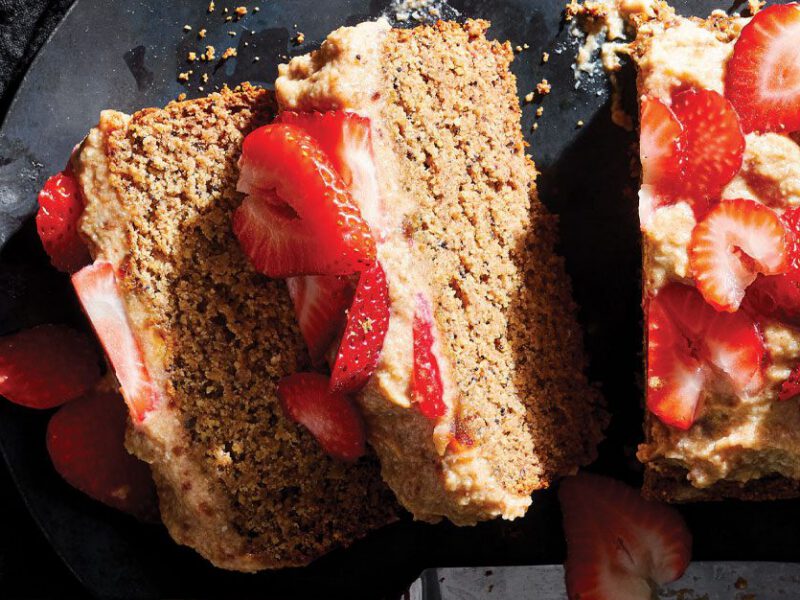 Almond Poppy Seed Cake topped with strawberries on a slate serving tray
