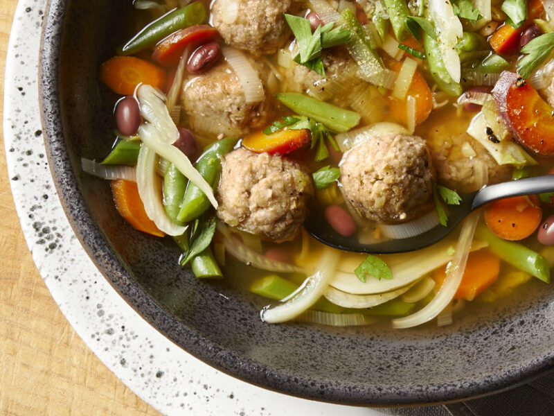 Vegan Italian Wedding Soup in a gray bowl against a wooden tabletop