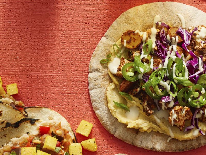 Mediterranean Tacos with Spicy Roasted Cauliflower on an orange wood background