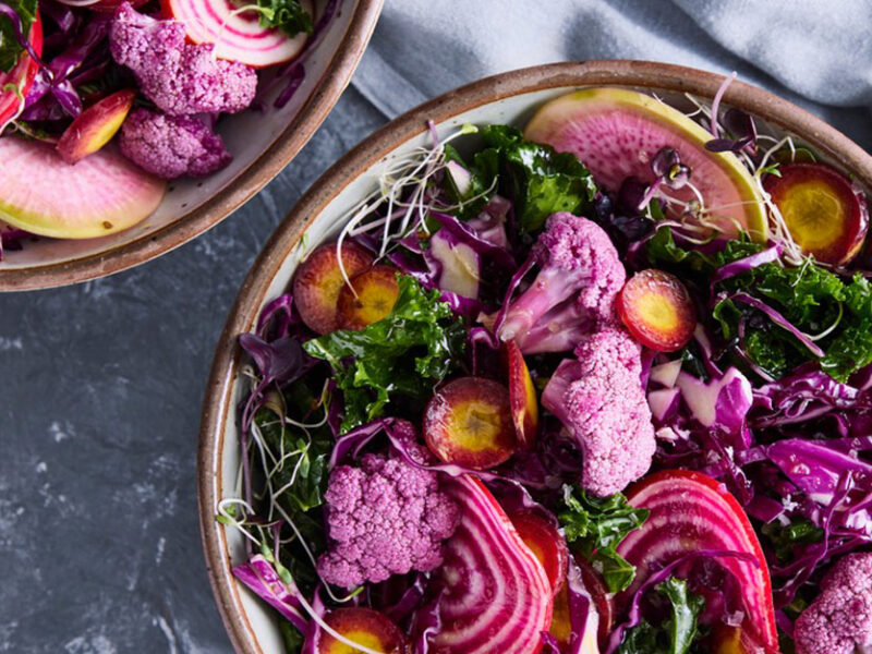 Raw Purple Power Salad in ceramic bowls against a gray background