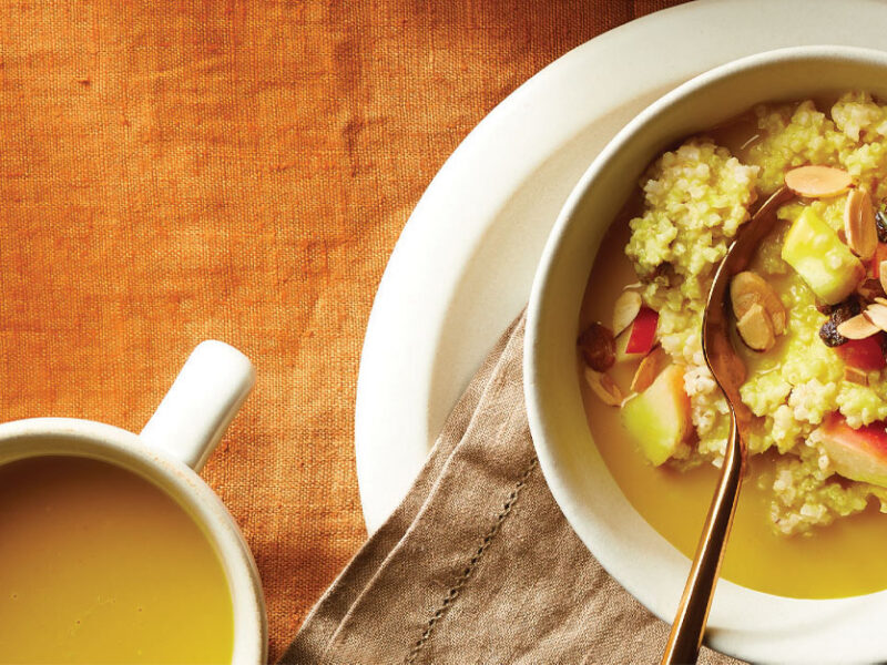 Golden Milk Millet Porridge in a white bowl with a mug of golden milk to the left
