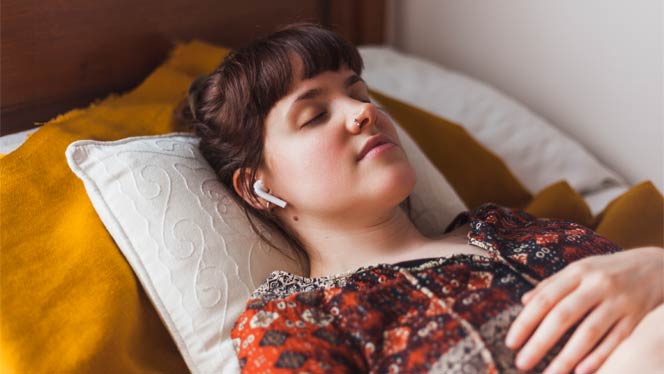 Young woman with headphones in lying in bed peacefully