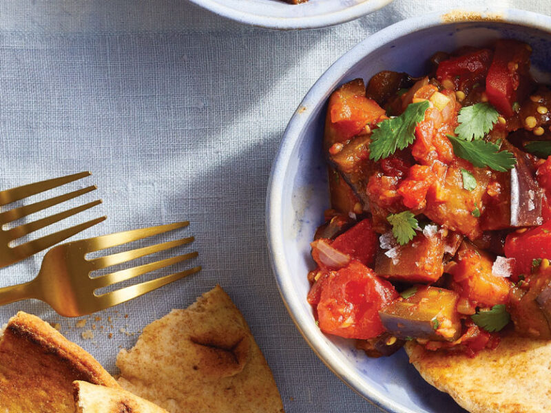 Warm Spiced Eggplant Salad in a small blue bowl with a side of pita bread