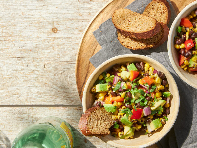 Grilled Corn Salad with Jalapeño Dressing in a cream colored bowl with a side of toasted bread slices