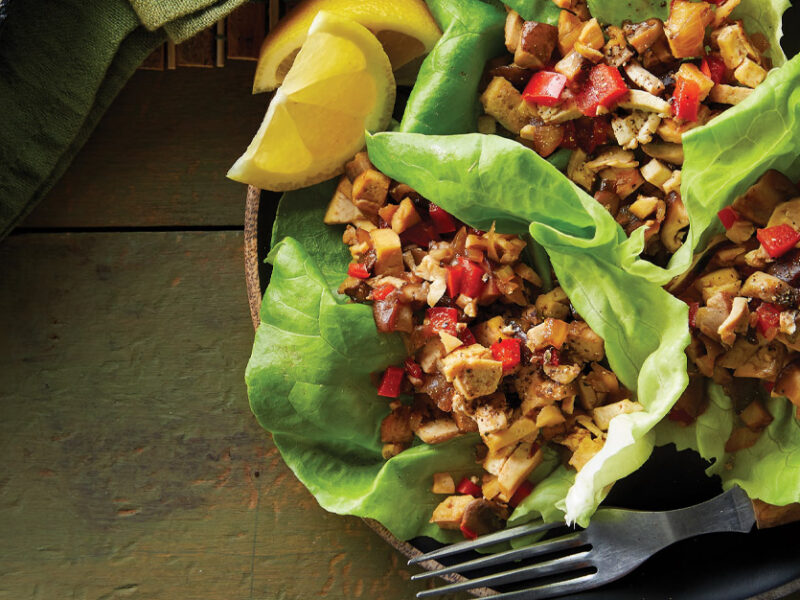 Vegan Sisig in lettuce cups on a dark green wooden background