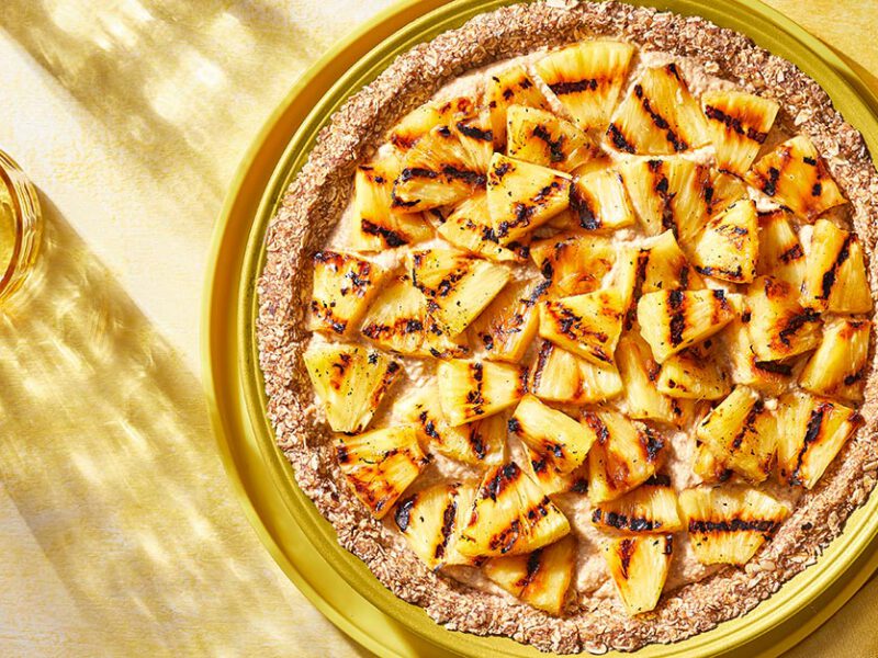 Grilled Pineapple Pie in a yellow pie tin against a yellow tabletop