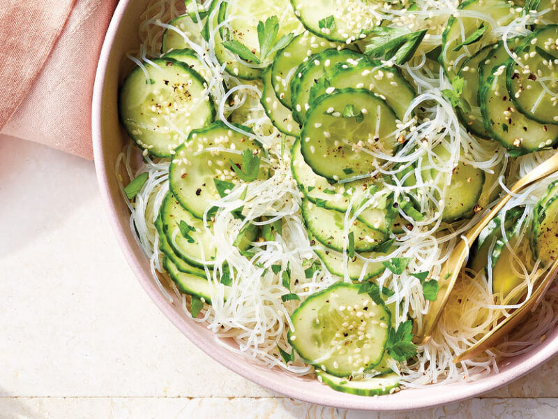 Cucumber and Glass Noodle Salad in a light pink serving bowl with gold metal tongs