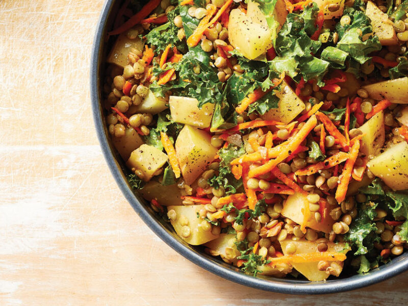 Kale and Lentil Salad with Potatoes in a gray ceramic bowl against a light wood tabletop
