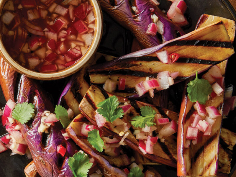 Grilled Chinese Eggplant with Spiced Vinegar Sauce on a dark grey plate