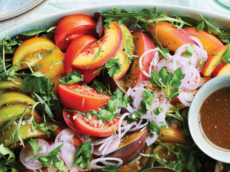 each and Tomato Salad on a light blue serving platter with a small bowl of vinaigrette