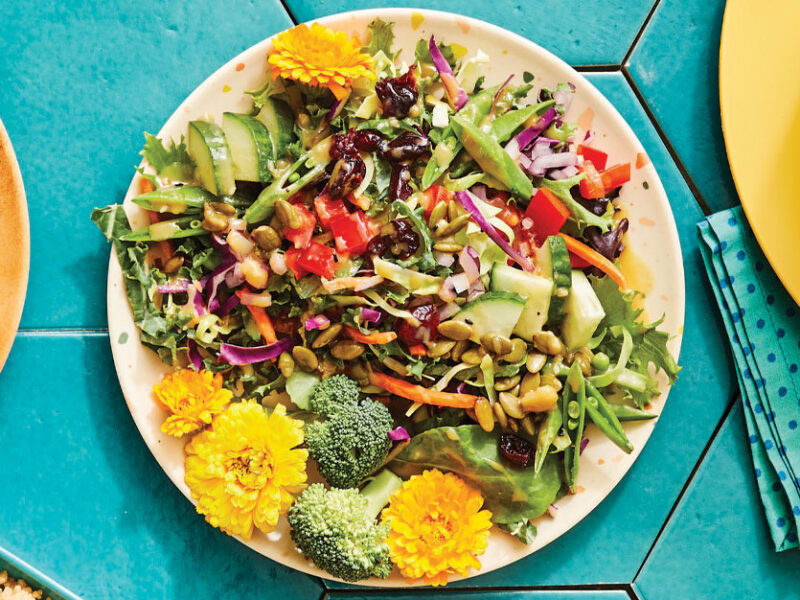 Kid-Friendly Edible Flower Salad on a whitte ceramic plate against teal tile background