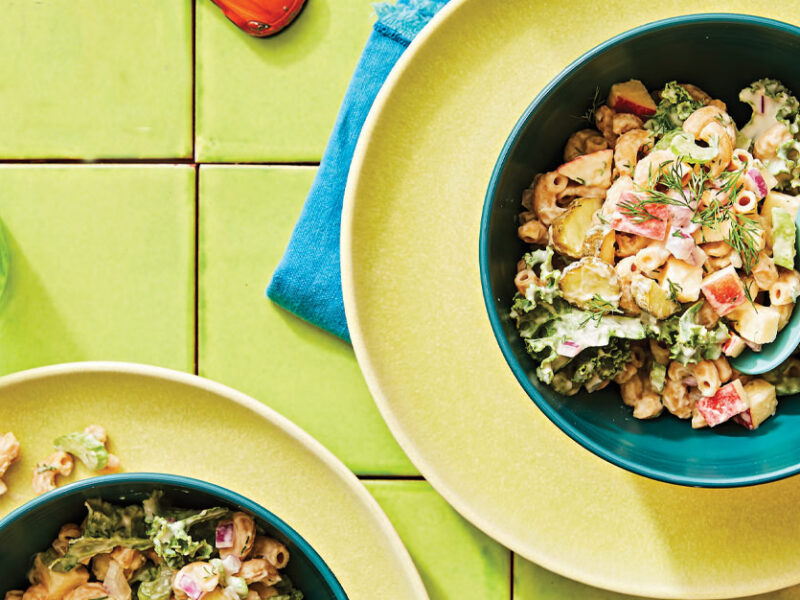 Dilly Vegan Macaroni Salad in a blue bowl on a yellow plate against a green tile background