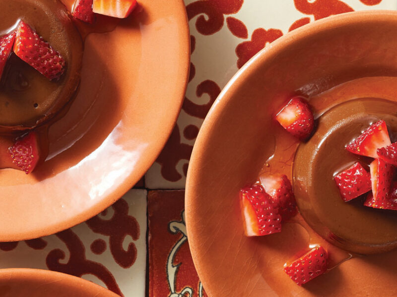 Chocolate Vegan Flan topped with strawberries on orange plates