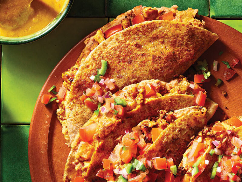Loaded Vegan Chalupas with Chipotle Queso on an orange plate against green tiles