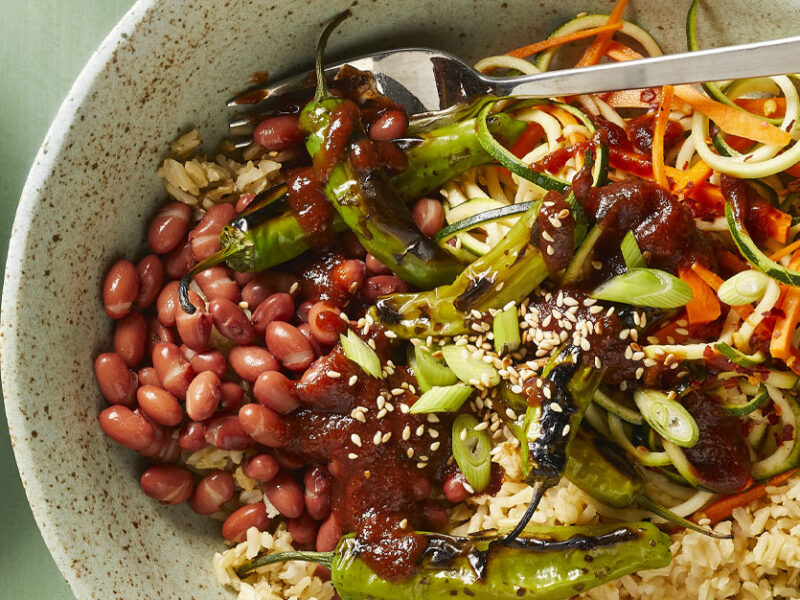 Vegan Korean BBQ Bowls with Shishito Peppers in a white ceramic bowl with a metal fork against a light green background