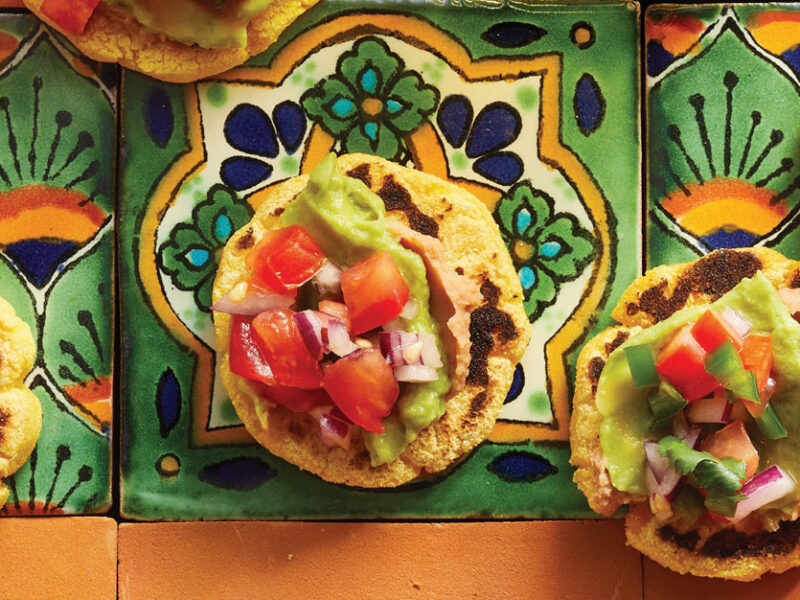 Homemade Vegan Sopes with Spicy Refried Beans on orange and green Mexican tiles