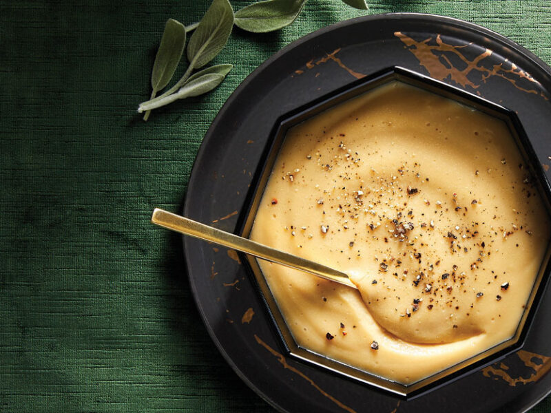Savory Chickpea Flour Gravy in a black hexagonal bowl with a metal spoon against a green velvet background