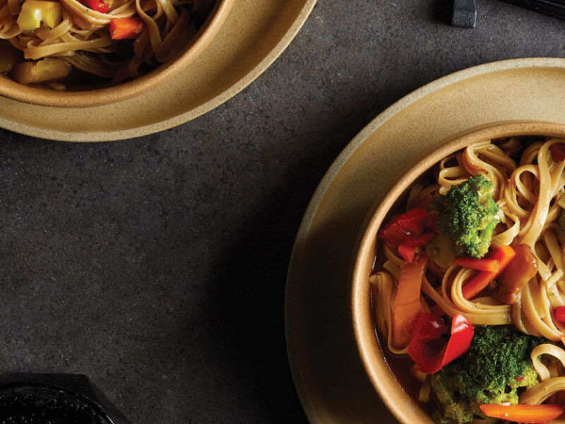 Brown Rice Noodle Bowls with Ginger-Garlic Sauce in light brown ceramic bowls against a dark gray background