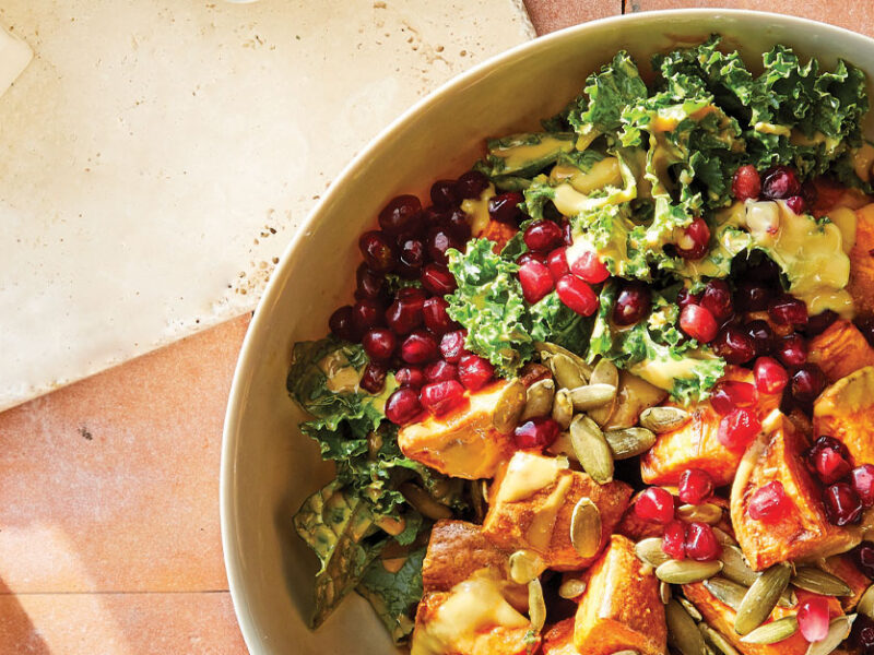 Cornucopia Kale Salad in a white ceramic bowl against a pink tile background