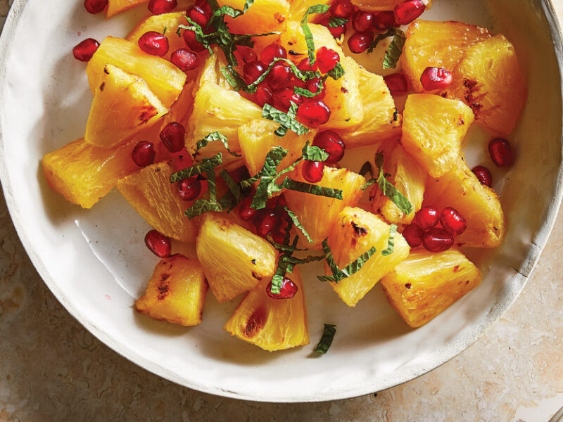 Roasted Pineapple with Fresh Mint and pomegranate arils in a white ceramic dish