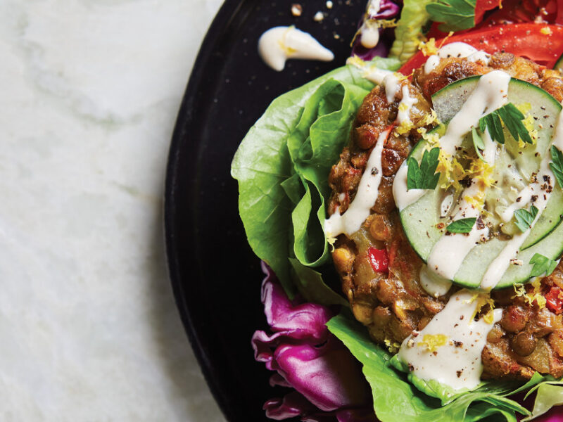 Lebanese Lentil Burgers in Cabbage Pockets on a black plate against a white marble background