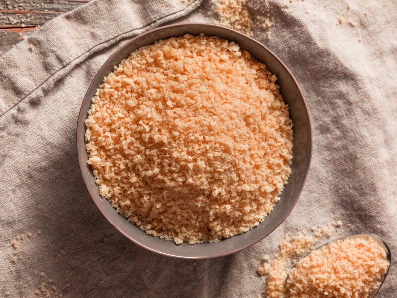 A bowl of whole wheat panko sitting atop a kitchen towel, shown from above