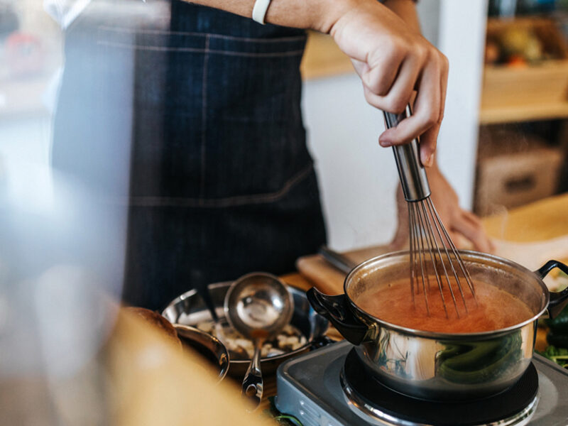 A person stands over a stove thickening a soup