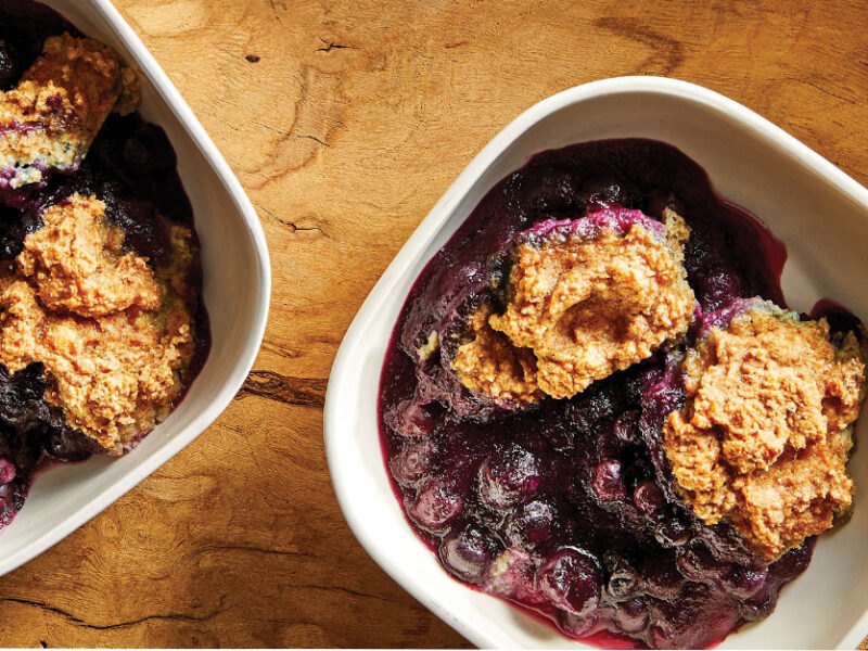 Vegan Blueberry Cobbler in square white bowls against a wooden tabletop