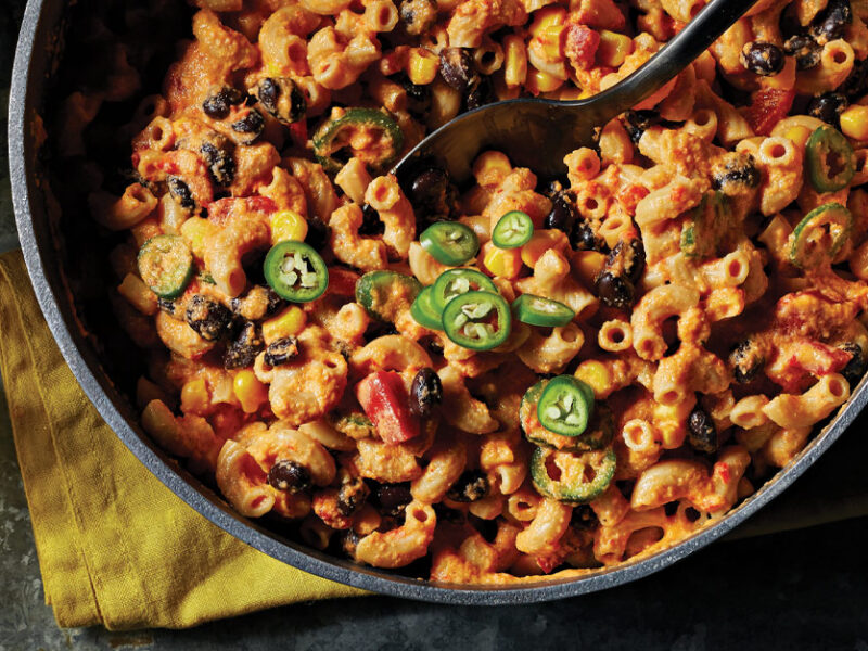 Vegan Chili Mac and Cheese in a large metal pot with a metal spoon stuck in the middle