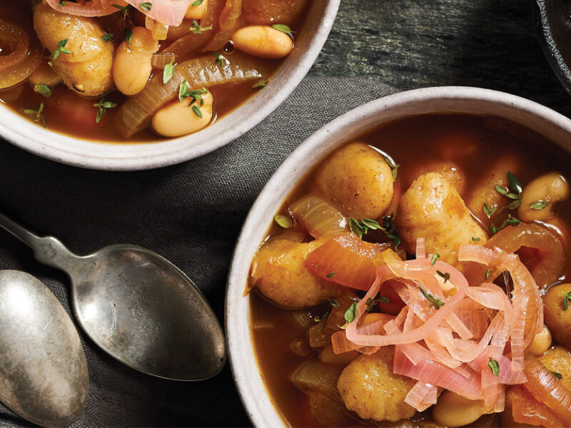 French Onion Gnocchi Soup in a white bowls against a dark gray background