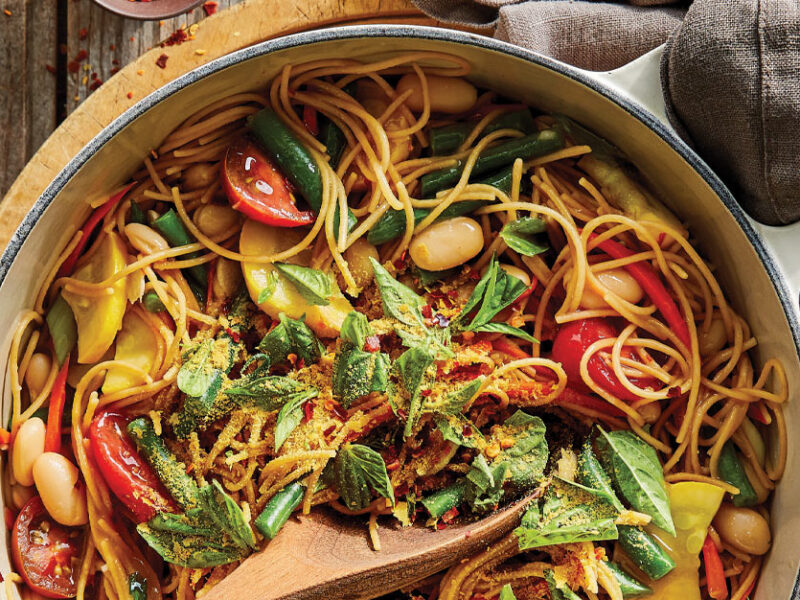 One-Pot Pasta with Spring Veggies in a white Dutch oven sitting on a wooden cutting board