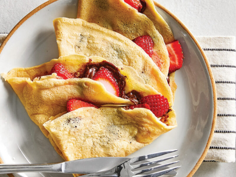 Gluten-Free Crepes stuffed with strawberries on a white ceramic plate