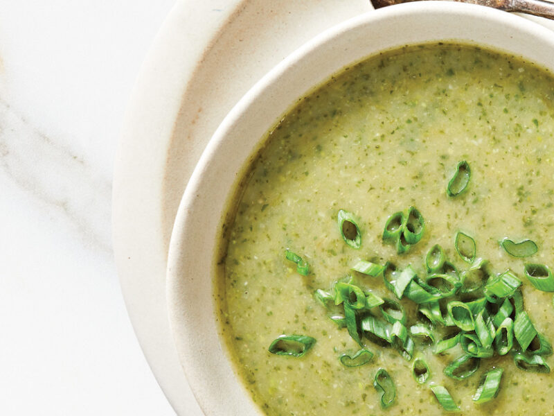 Green Velvet Soup topped with scallions in a white ceramic bowl